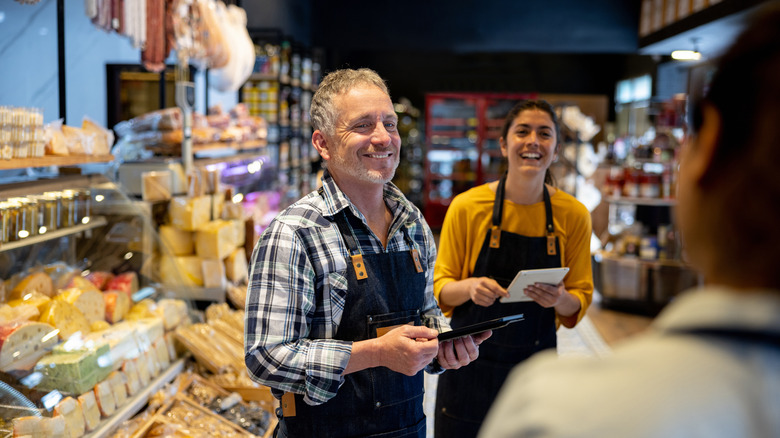 two store employees smile at a customer near the bread aisle