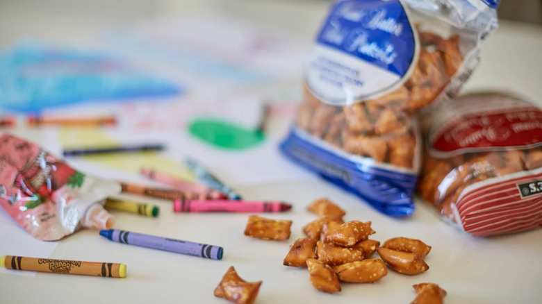 A bag of Trader Joe's Peanut Butter Filled Pretzel Nuggets next to crayons and pretzels