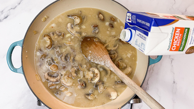 pouring chicken broth into sauce