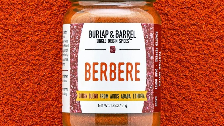 Jar of berbere powder sitting on bright red berbere