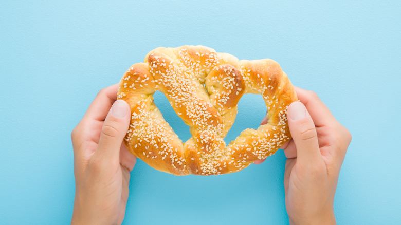 a person holding a soft pretzel on a blue background