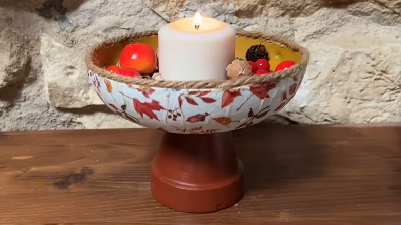 Upcycled frying pan on a stand with a candle and plastic fruit