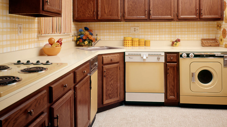 View of '70s kitchen where you can see the harvest gold stovetop, dishwasher, and other appliances