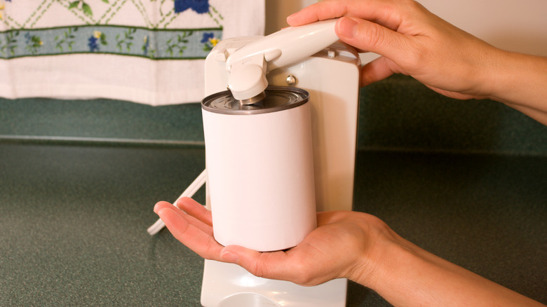 Hands using an electric can opener