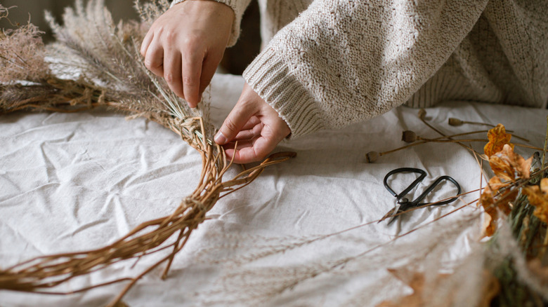 A woman's hands making an autumn wreath