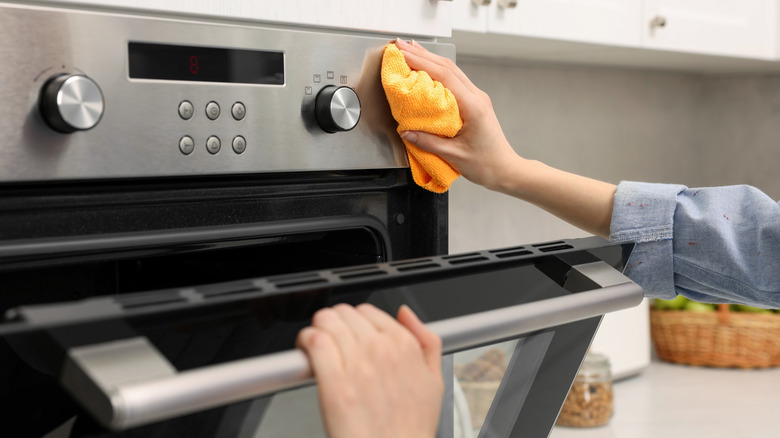 Person wiping stove with orange cloth