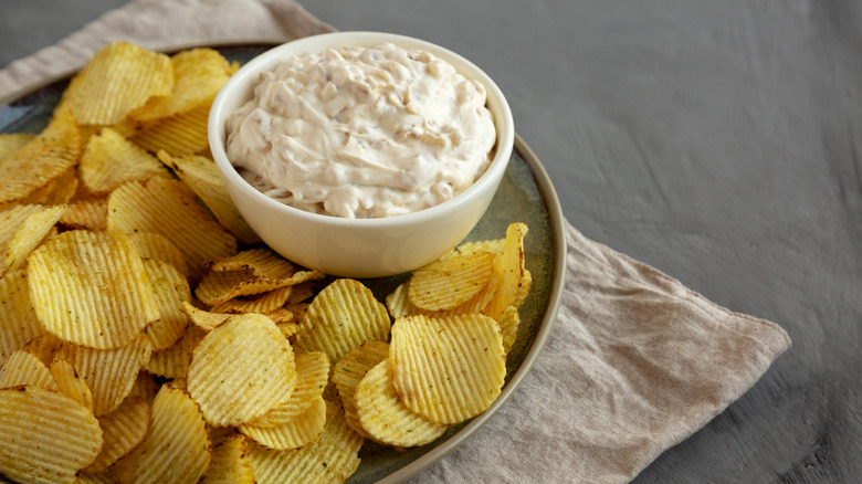 bowl of caramelized onion dip with potato chips on a plate