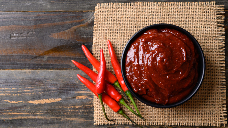 Gochujang paste in a bowl next to chilis