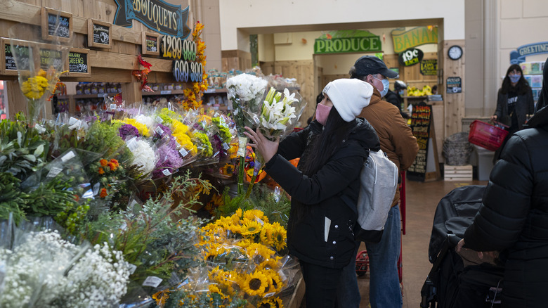 A woman selects fresh flowers to buy in a Trader Joe's supermarket in New York City.