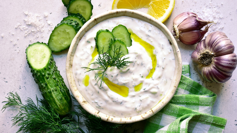 overhead view of bowl of tzatziki with cucumbers, lemon, and garlic