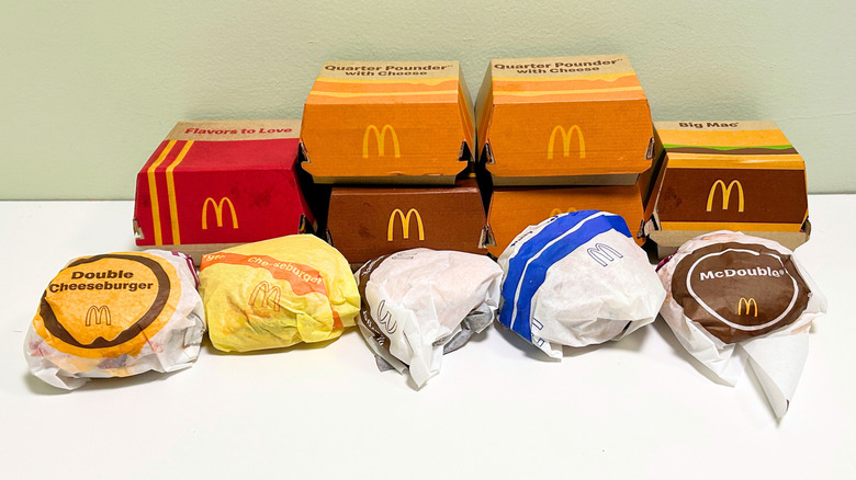Several McDonald's burgers lined up together still in their boxes and wrappers