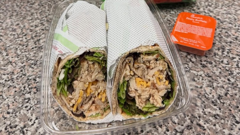 A Cool Wrap from Chick-fil-A in a takeout box on a table with a Zesty Buffalo sauce container on the side