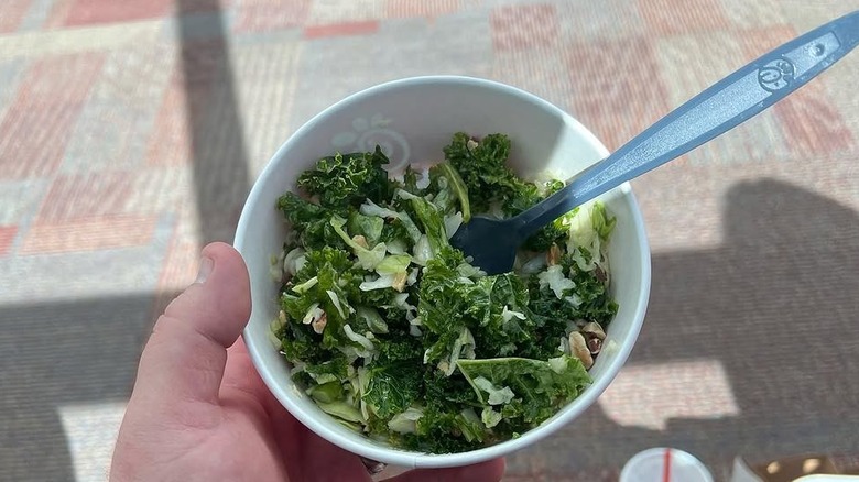 A person holding a takeout container full of the Kale Crunch Side from Chick-fil-A