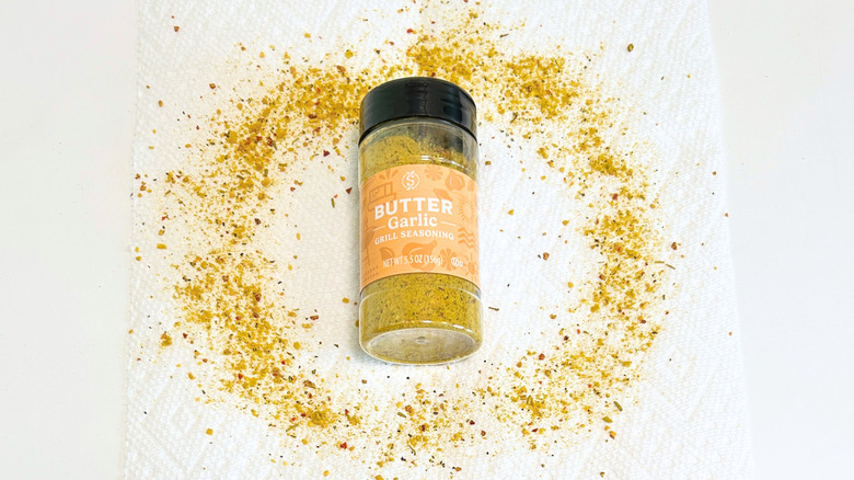 A bottle of Stonemill Butter Garlic Grill Seasoning amongst sprinkles of seasoning