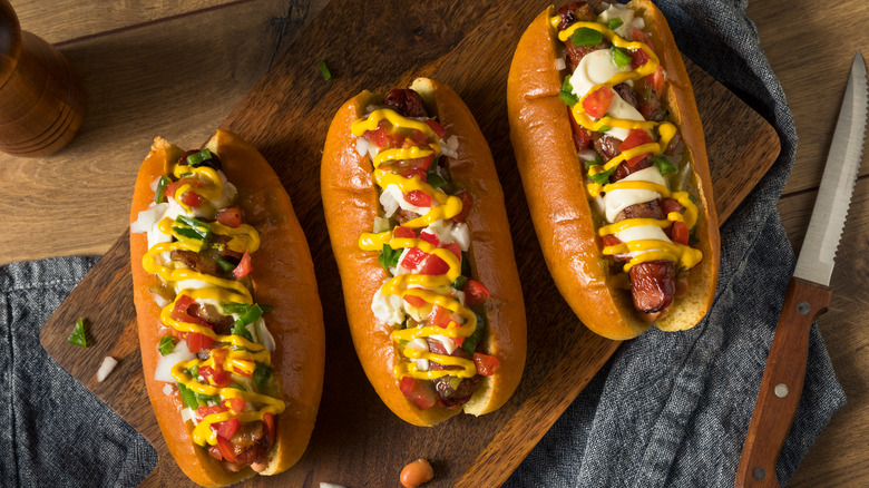 three sonoran hot dogs on a cutting board