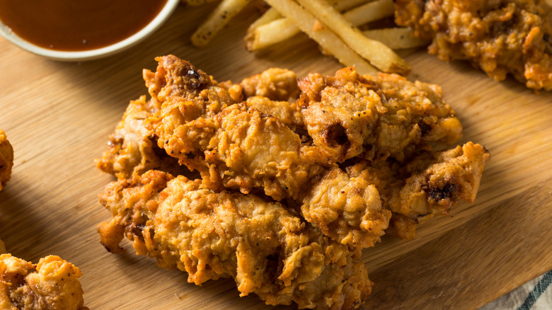 Deep fried Idaho finger steaks on a wooden board, with french fries and dipping sauce