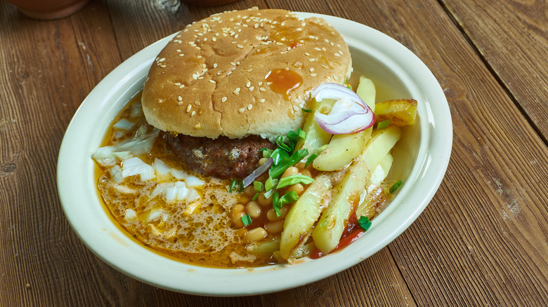 A plate with a slopper served with beans and fries