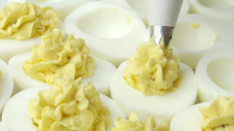 piping yolk into deviled eggs
