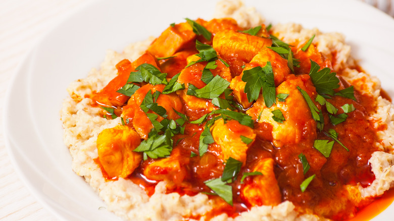 Meat and sauce on oatmeal in a white bowl