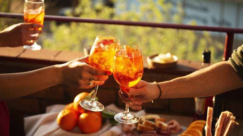 Two people clink glasses of Aperol