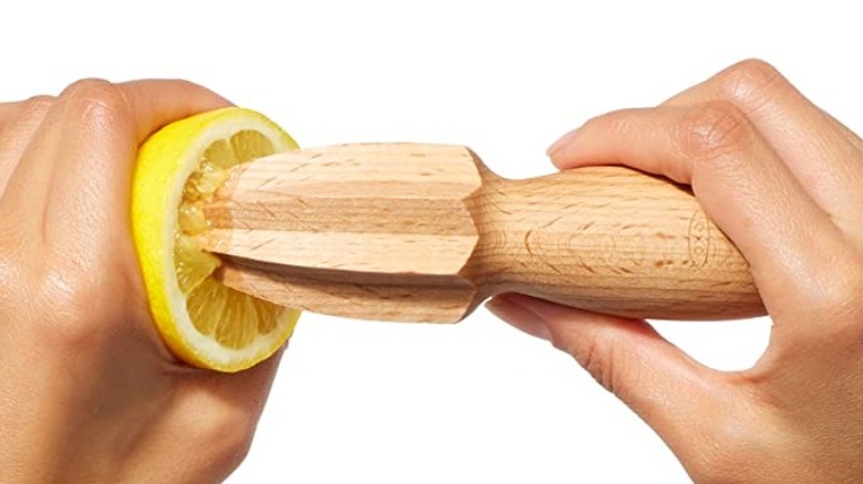 Hands using wooden lemon juicer