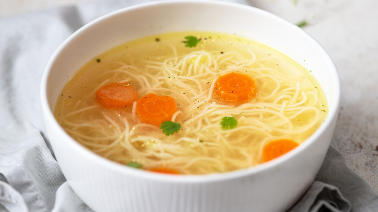 Bowl of chicken noodle soup on white background
