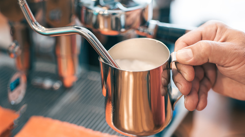 barista frothing milk pitcher