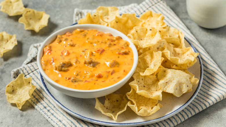 A bowl of spicy sausage cheese dip, surrounded by chips