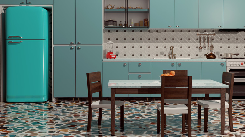 A retro kitchen with bright blue fridge and muted blue cabinets