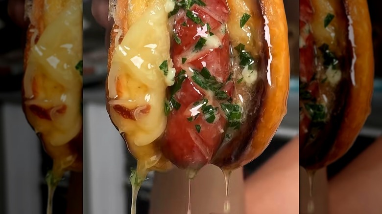 A grilled cheese hot dog dipped in, and dripping with, melted butter
