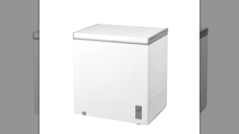 A three quarter view of a white rectangular chest freezer with gray insulating trim