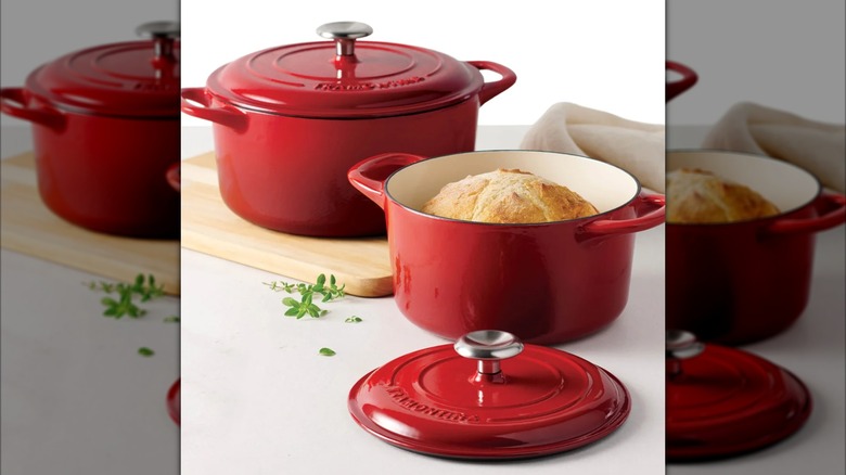 Two red Tramontina Dutch ovens, with the smaller one filled with bread