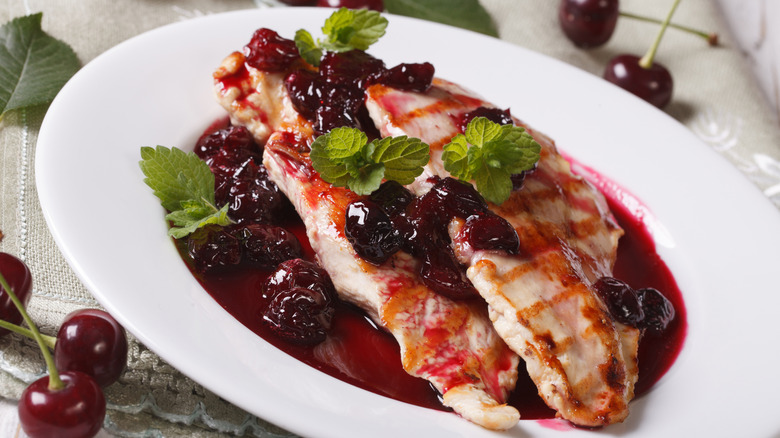 Chicken with cherry glaze and cherries on white plate