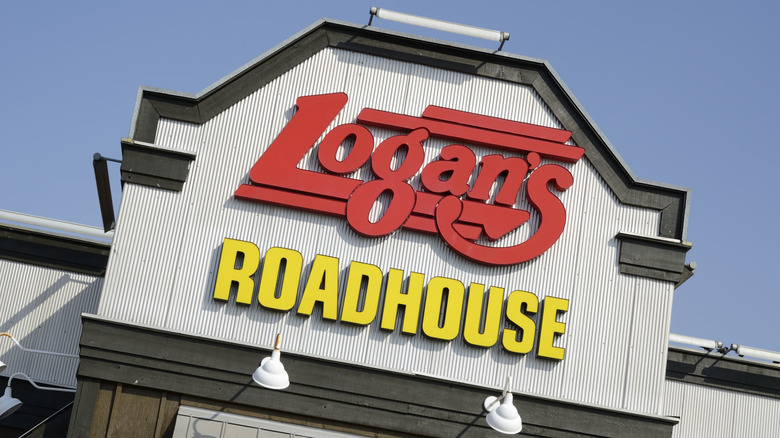 The red and yellow bold signage on a Logan's Roadhouse against a blue sky.