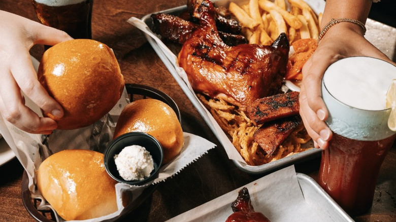 A meal and rolls plus two drinks on a wooden table