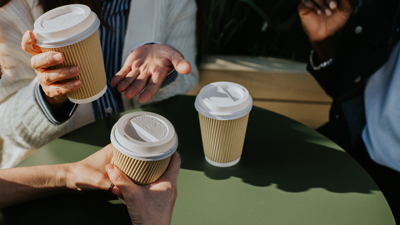 Three people with takeout coffee cups