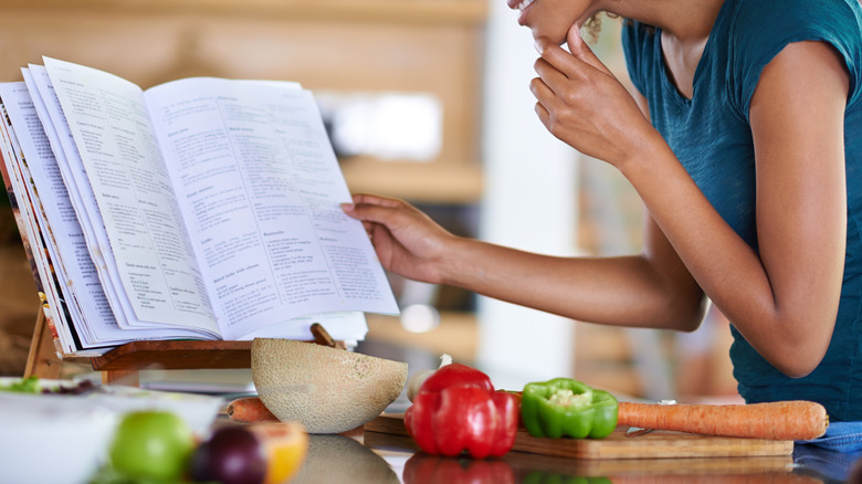 woman looking at a cookbook on a stand