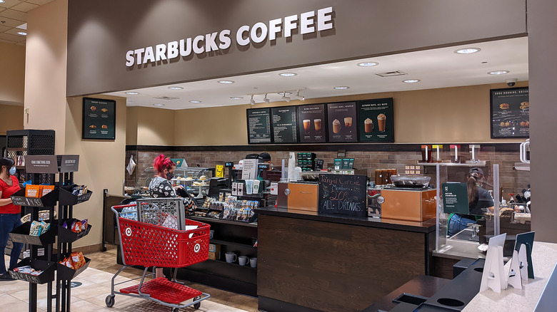 A customer with a Target shopping cart ordering at Starbucks