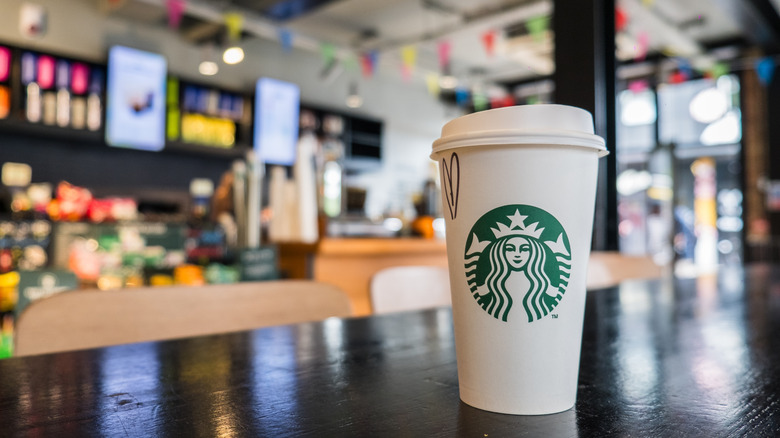 A Starbucks logo cup sits on a table at a cafe