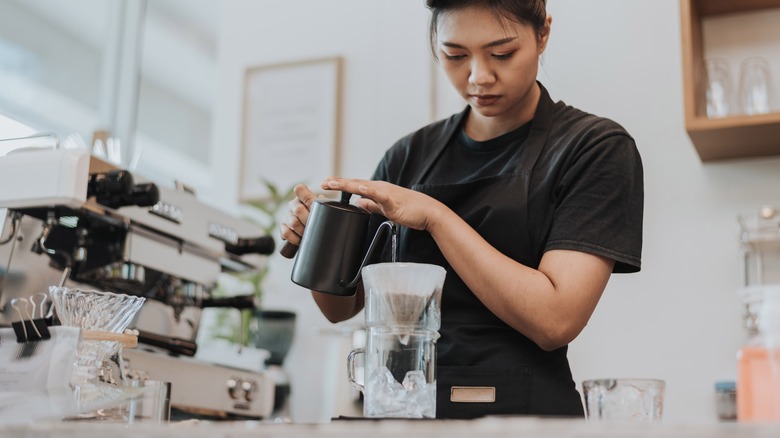 Female barista making pour-over coffee light furnishings