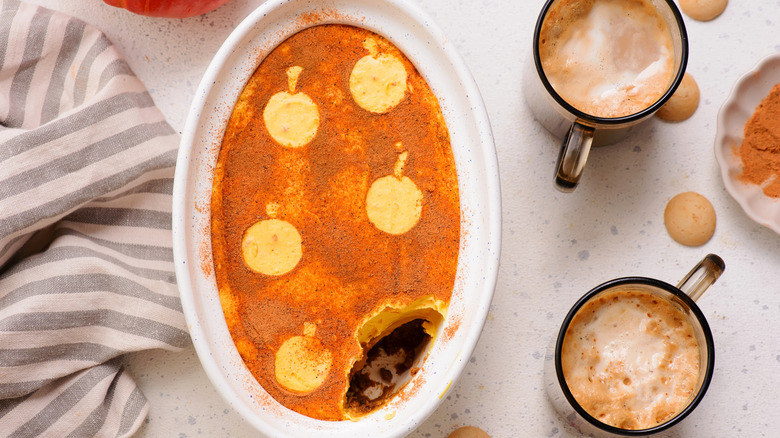 A dish full of pumpkin tiramisu on a marble table with two cups of coffee on the side