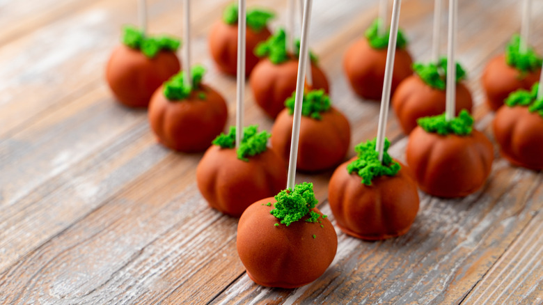 Orange pumpkin cake pops on a wooden table