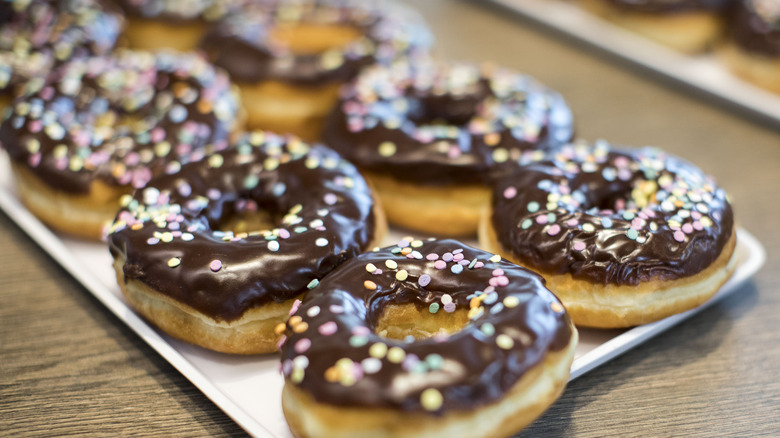 Several chocolate glazed donuts on rectangular plate
