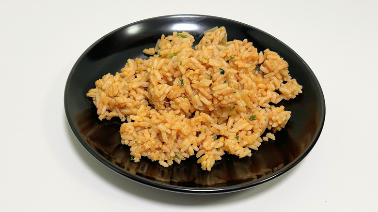 A black plate of Texas Roadhouse seasoned rice against a white background