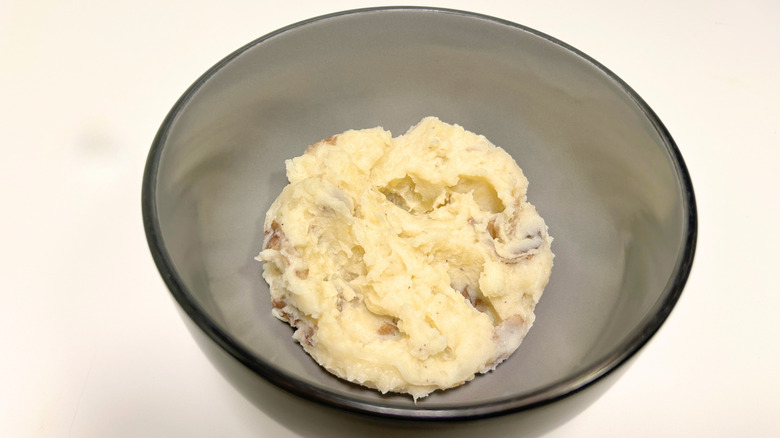 A black bowl of Texas Roadhouse mashed potatoes against a white background