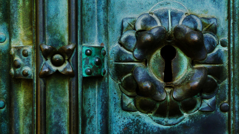 Closeup of a tarnished copper door lock that's turned blue-green in color