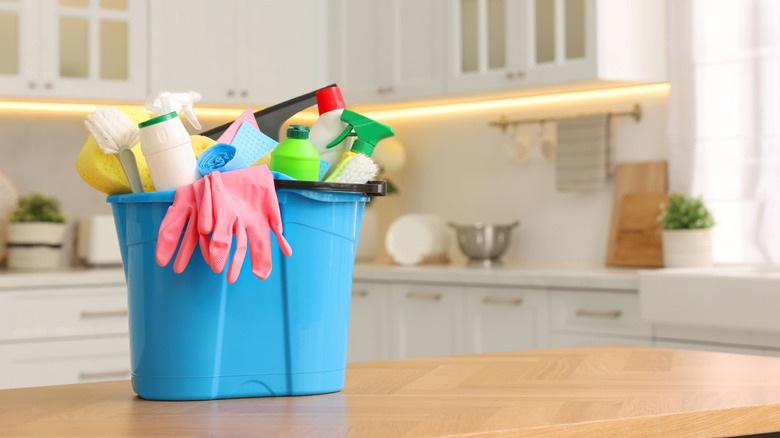 A bucket of cleaning supplies on a kitchen table