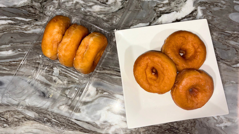 A package of donuts next to a plate of three donuts against a countertop