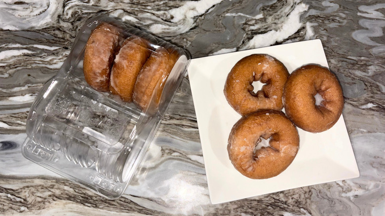 A package of apple cider donuts next to a plate with three donuts