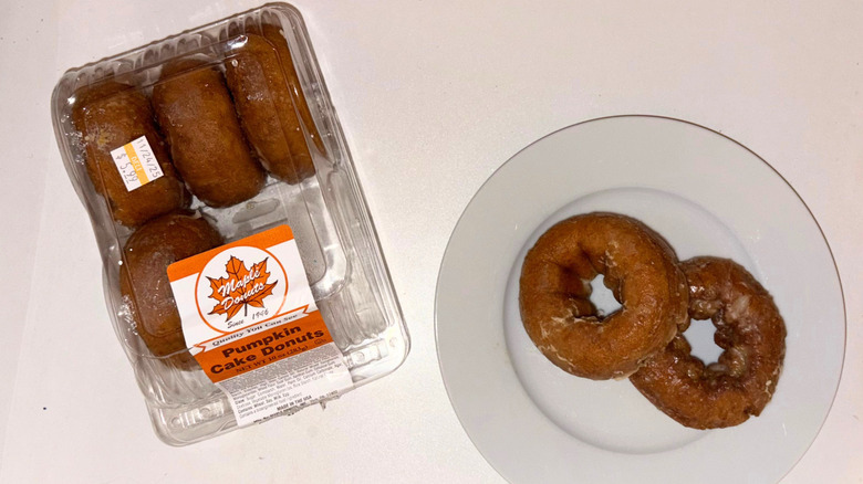 A package of apple cider donuts next to a plate with two donuts